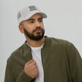 Male model wearing Respect Existence or Expect Resistance Silver Trucker Hat with olive jacket