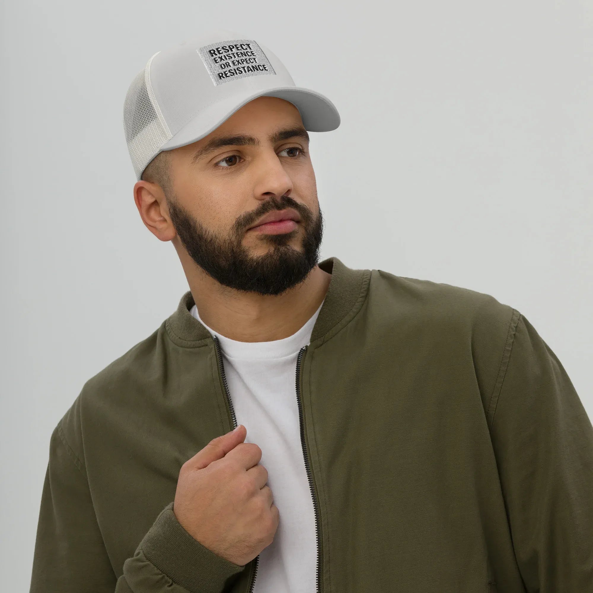Male model wearing Respect Existence or Expect Resistance Silver Trucker Hat with olive jacket