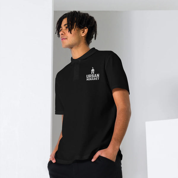 Front view of a man wearing Urban Minaret unisex black pique polo shirt with white brand logo on the chest.